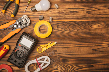 Electrician equipment on a wooden background with copy space.Top view.Electrician tool set.Multimeter, tester,screwdrivers,cutters,duct tape,lamps,tape measure and wires.Flet lay.Concept building © Avocado_studio