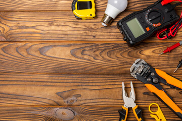 Electrician equipment on a wooden background with copy space.Top view.Electrician tool set.Multimeter, tester,screwdrivers,cutters,duct tape,lamps,tape measure and wires.Flet lay.Concept building © Avocado_studio