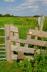 Naklejka premium Tienhoven, The Netherlands, August 23, 2023: wooden contruction enabling hikers to cross a fence in Tienhovense Plassen nature reserve