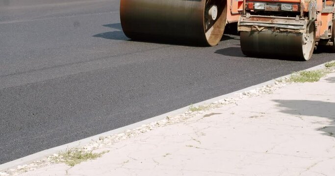 Asphalt paver machine on a road construction site. Road building asphalt paver is laying a new layer of asphalt, Road rollers drive on a new road. Heavy machinery. 