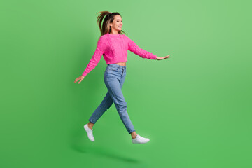 Fototapeta na wymiar Full size photo of good mood satisfied girl wear pink pullover jeans go shopping look empty space isolated on green color background