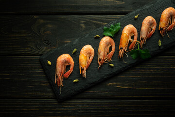 Boiled shrimp on a black sorting board with parsley and fragrant spices. Hotel table setting...