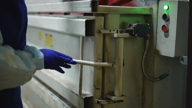 Unrecognizable woman closing door of hydraulic press machine pressing start button. Young Caucasian worker in uniform sorting garbage on recycling station indoors processing used trash