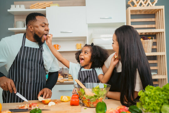 Kind African American Parents Teaching Their Adorable Daughter How To Cook Healthy Food, Free Space Of Kitchen, Happy Black People Family Preparing Healthy Food In Kitchen Together