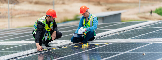 Professional specialist technician engineer working to maintenance checking and installing solar roof panel on the factory rooftop under sunlight. Worker inspection team for smart grid ecology energy