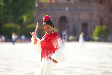 Young black woman dressed as a flamenco gypsy in a square in Seville, Spain. She wears a beige...