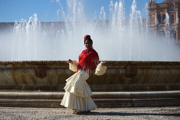 Young black woman dressed as a flamenco gypsy in a famous square in Seville, Spain. She is wearing...