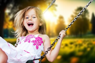 Little kid having fun and swinging at hot summer day.