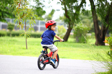 Asian Little boy riding a red bicycle in park