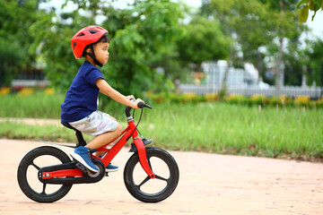 Asian Little boy riding a red bicycle in park