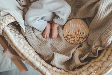 Legs of a newborn baby and a wooden board with the inscription: hello world