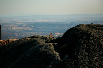 The roof of the house with the cross peeks out from behind a huge boulder in the Monsanto medieval village, Portugal.