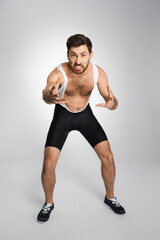 Young wrestler in black and white tight singlet getting ready to attack in studio. Front view of...