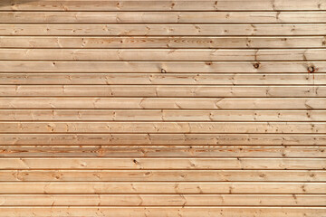 Texture of the wooden wall made of pale orange panels with bevel edges as a background