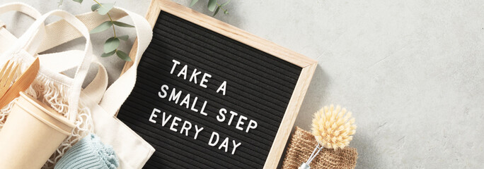 Take a small step every day letter board and zero waste no plastic accessories on grey stone...