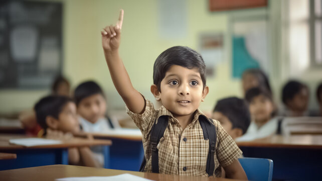 Joyful indian cute school kid boy raising pointing finger up in class.
