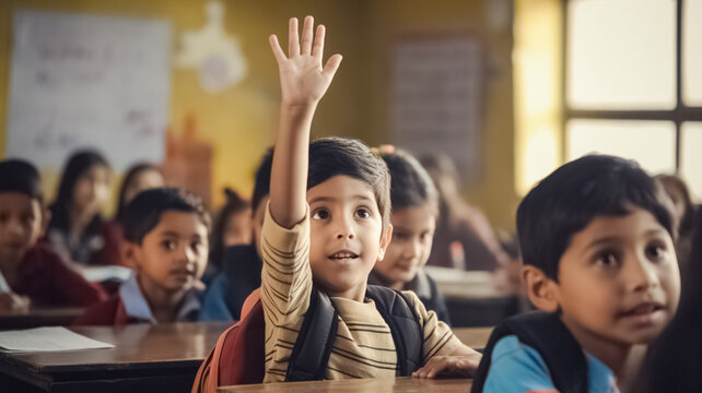 Small indian boy kid in school classroom raising hand up to answer teacher.



