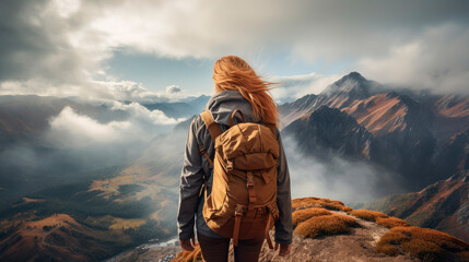 Young woman traveler on a mountain summit enjoying freedom, back view