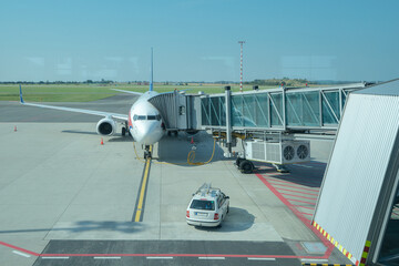 A view from the airport concourse of a plane being prepared for departure. The photo shows a plane,...
