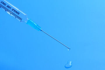 Single use syringe isolated on blue background.