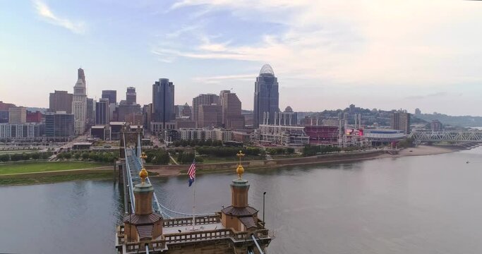 American Flag on top of suspension bridge with downtown Cincinnati, Ohio skyline, aerial drone footage