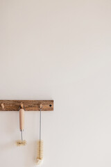 Wood hook rack with sustainable cleaning brush hanging on a white wall on the modern style kitchen background. Smart organisation storage ideas. Eco friendly life..