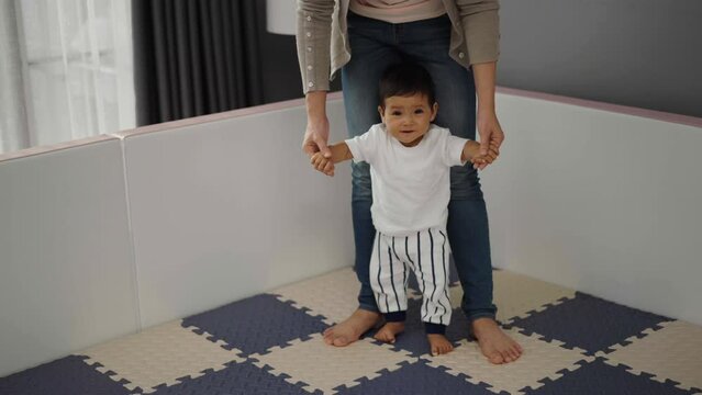 infant baby learning to standing with mother on a floor