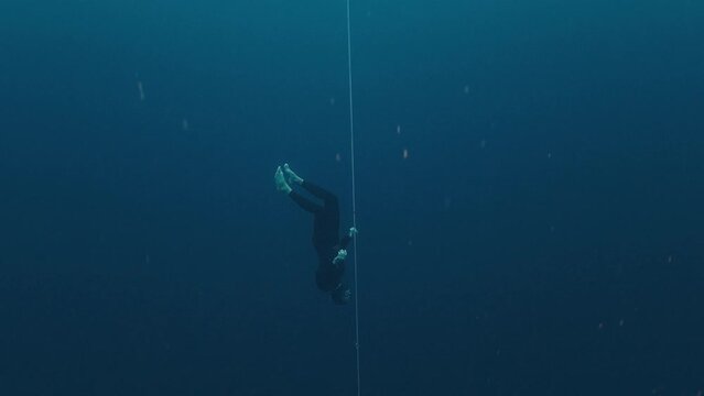 Male freediver descending along the rope during free diving work out in the open sea