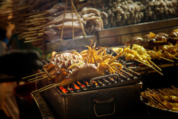 grilled squid with curry sauce on chacoal barbecue in night street food market