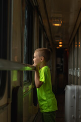 Adorable boy looking out train window outside and trave