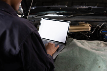 back view mechanic using laptop computer with white screen for checking and fixing a car in automobile repair shop