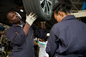 African mechanic workers fixing and checking a car or tire in automobile repair shop