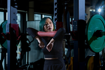 depressed athletic asian woman after practicing routine weightlifting and overtrain at modern gym,...