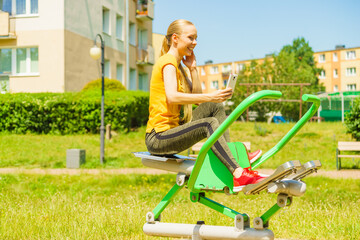 Girl doing exercises outdoor, holding phone