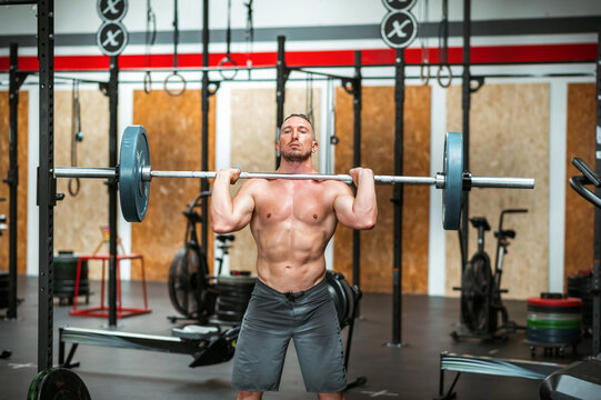 Strong man doing clean and jerk movement in gym