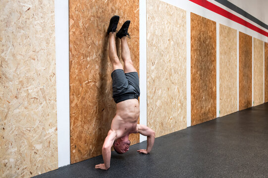 Strong man doing handstand push up in gym