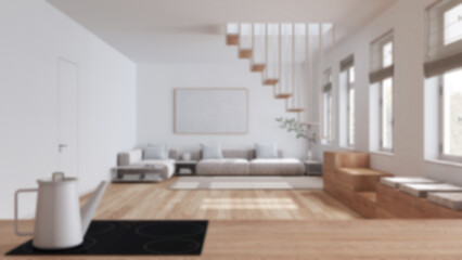 Blurred background, kitchen work top with induction hob and teapot close up. Nordic living room. Sofa and minimal staircase. Scandinavian interior design