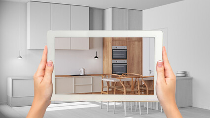 Augmented reality concept. Hand holding tablet with AR application used to simulate furniture and design products in total white background, minimal kitchen with island - obrazy, fototapety, plakaty