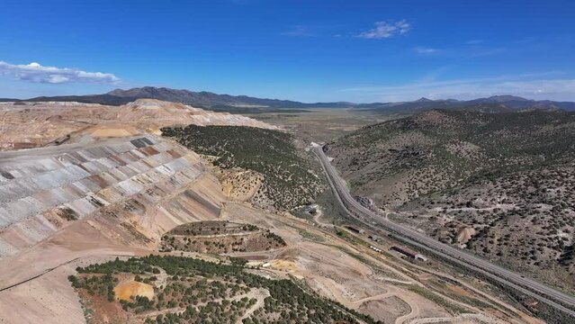 Aerial gold copper mine to mountain Ely Nevada 4K fast. Copper and gold discovered in Ely Nevada in late 1800's. Boom town along historic Pony Express trail. Ore transported to Japan for smelting.