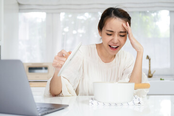 shocked scared upset young asian woman made mistake cook pot indoors inside house kitchen