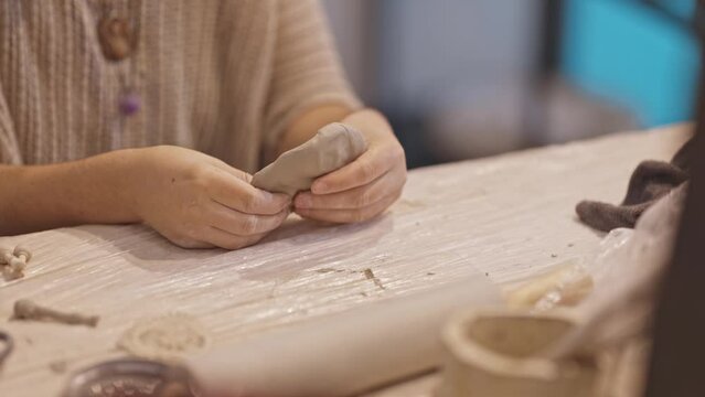 A person kneads clay on the table