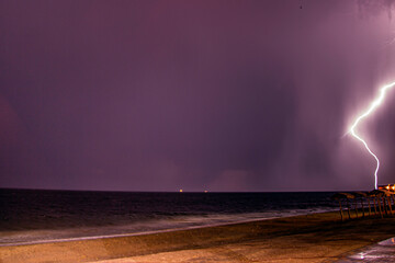 Lightning to the right on the sea horizon at night	
