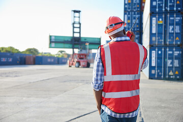 back view African factory worker or engineer using walkie talkie in containers warehouse storage