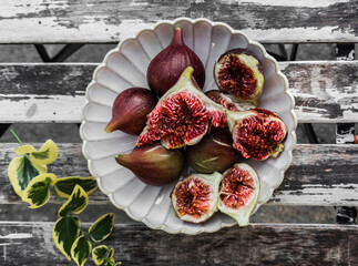 Ripe juicy figs in a plate on a wooden table, top view