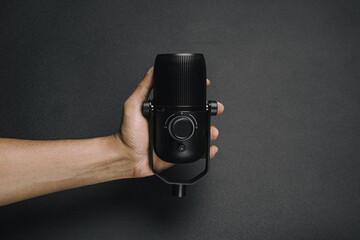 man hand holding condenser mic with plain black background