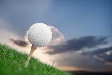 Golf white ball on tee on green grass