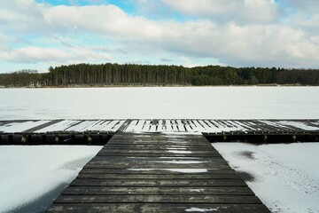 Widok na pomost, pokryte śniegiem jezioro i las zimą