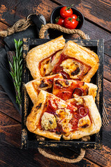 Puff pastry tart pizza  with artichoke, mozzarella, tomatoes and cheese sliced in a wooden tray....