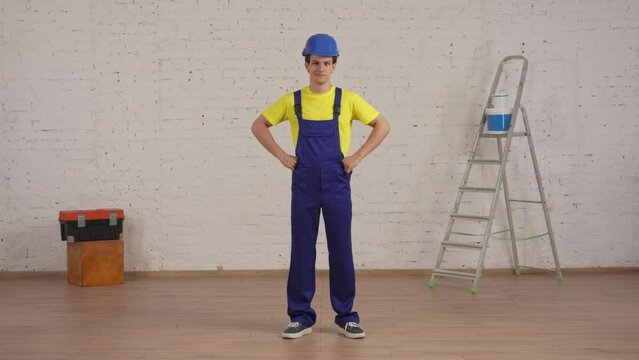 Full length video of a smiling young construction worker standing in the room under renovation with his hands on his hips.