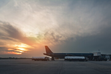 Modern international airport in the early morning with an airplane at the terminal gate preparing to take off.